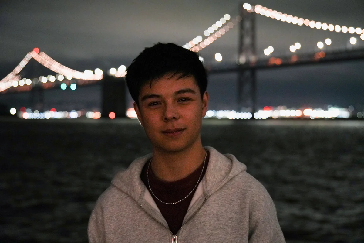 Sam at night in front of the Bay Bridge in San Francisco.